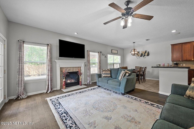 8719 Derry Dr, Jacksonville, FL 32244 - living area with a textured ceiling, wood finished floors, a ceiling fan, a tile fireplace, and baseboards