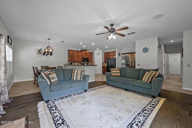 8719 Derry Dr, Jacksonville, FL 32244 - living area featuring dark wood-style flooring, a chandelier, ceiling fan, baseboards, and a textured ceiling