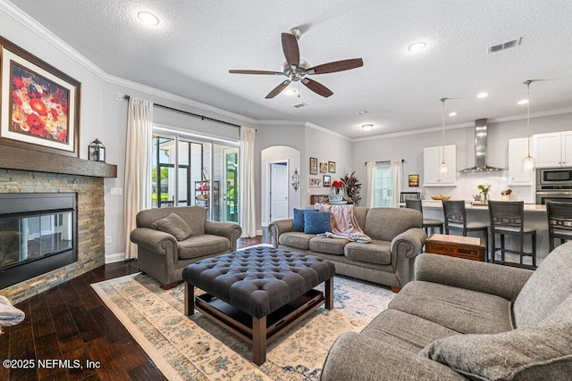 2035 Arden Forest Pl, Fleming Island, FL 32003 - living room featuring ceiling fan, wood-type flooring, arched walkways, a fireplace, and a textured ceiling