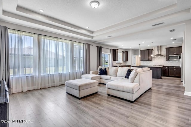 23 Catesby Ln, Saint Augustine, FL 32095 - living room featuring a tray ceiling, light wood-type flooring, healthy amount of natural light, recessed lighting, and a textured ceiling