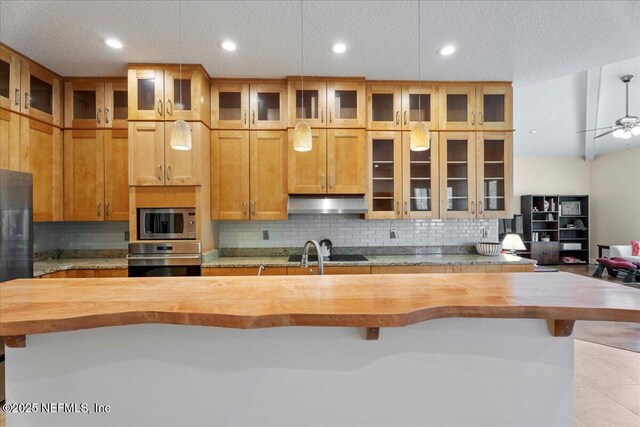 207 Towers Ranch Dr, Saint Augustine, FL 32092 - kitchen with butcher block counters, stainless steel appliances, under cabinet range hood, backsplash, and a textured ceiling