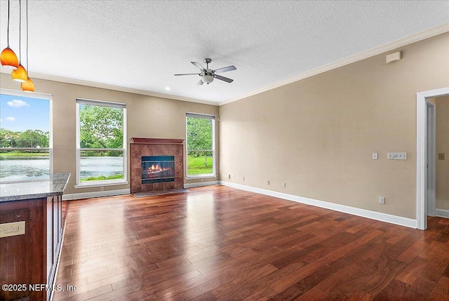 1476 Mallard Landing Blvd, Saint Johns, FL 32259 - unfurnished living room with a ceiling fan, ornamental molding, dark wood-style flooring, a textured ceiling, and a tiled fireplace