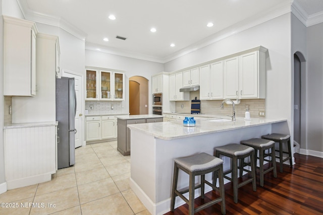 1867 Paradise Moorings Blvd, Middleburg, FL 32068 - kitchen with arched walkways, appliances with stainless steel finishes, a peninsula, a sink, and under cabinet range hood