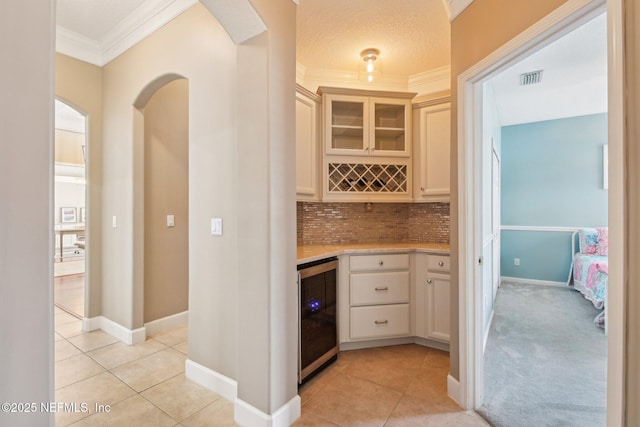 1867 Paradise Moorings Blvd, Middleburg, FL 32068 - indoor dry bar featuring wine cooler, ornamental molding, light tile patterned floors, backsplash, and arched walkways