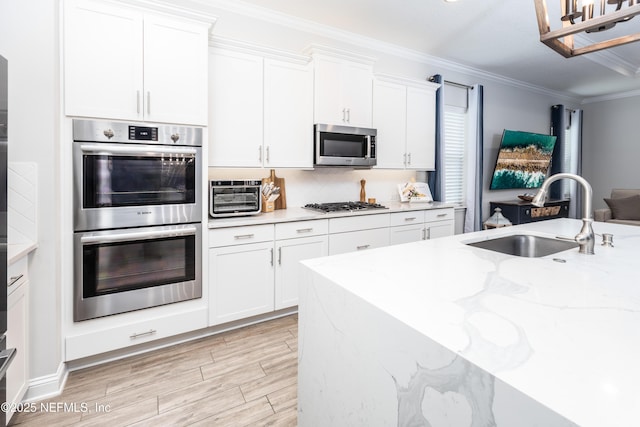 103 Tarbert Ln, Saint Augustine, FL 32092 - kitchen featuring appliances with stainless steel finishes, a sink, crown molding, light wood-type flooring, and white cabinetry