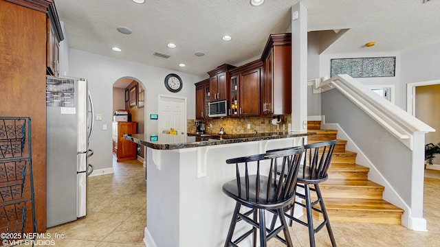 200 Huntston Way, Saint Johns, FL 32259 - kitchen featuring stainless steel appliances, arched walkways, decorative backsplash, a breakfast bar, and dark stone countertops