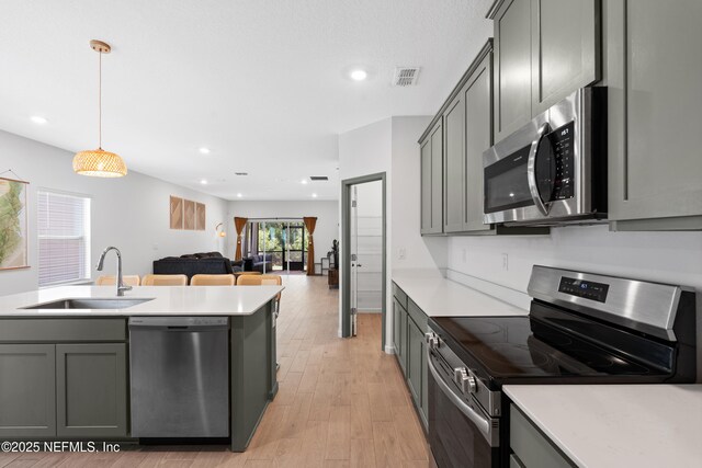 727 Lake Sinclair St, Saint Augustine, FL 32084 - kitchen featuring stainless steel appliances, a sink, light countertops, gray cabinetry, and light wood-style floors