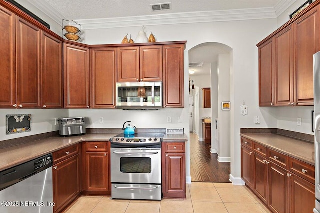 2005 Rivers Own Rd, Saint Augustine, FL 32092 - kitchen featuring stainless steel appliances, arched walkways, dark countertops, ornamental molding, and light tile patterned flooring