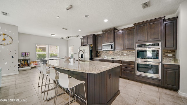 514 Heron Landing Rd, Saint Johns, FL 32259 - kitchen featuring stainless steel appliances, tasteful backsplash, light tile patterned floors, dark brown cabinetry, and recessed lighting