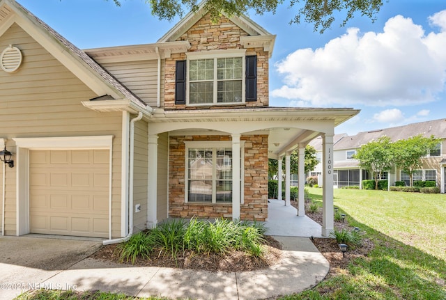 11000 Castlemain Cir E, Jacksonville, FL 32256 - view of front of property featuring stone siding, a porch, a front lawn, and a garage