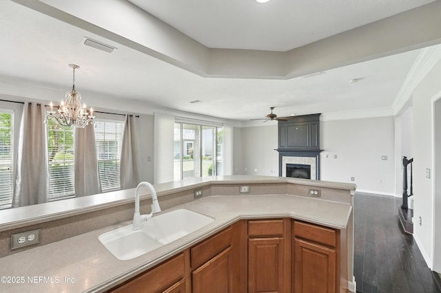 11000 Castlemain Cir E, Jacksonville, FL 32256 - kitchen with a sink, a fireplace, open floor plan, brown cabinetry, and ornamental molding