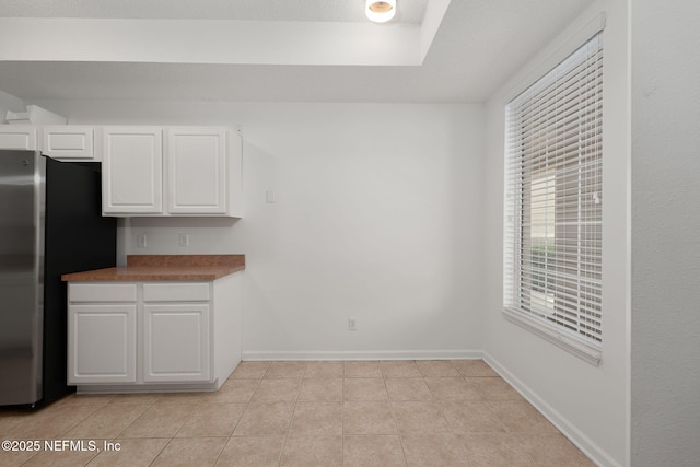 204 Augusta Cir, Saint Augustine, FL 32086 - kitchen featuring freestanding refrigerator, white cabinetry, light tile patterned floors, and baseboards