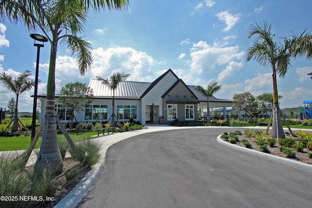 view of front of property featuring metal roof and curved driveway