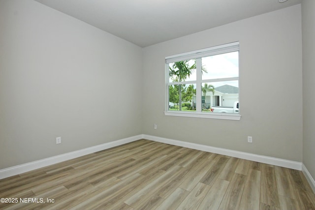 spare room featuring baseboards and light wood-style floors