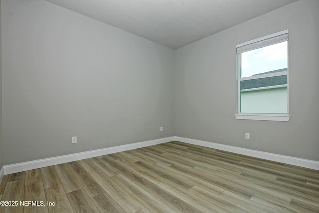 spare room featuring baseboards and wood finished floors