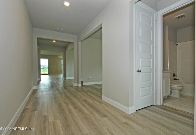 hallway featuring light wood finished floors, recessed lighting, and baseboards