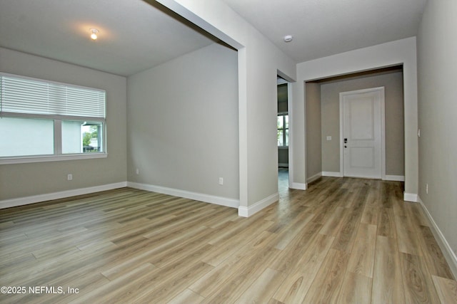 empty room with light wood-type flooring and baseboards