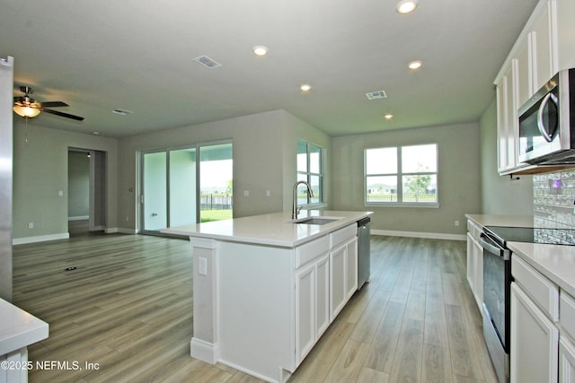 kitchen featuring stainless steel appliances, a sink, open floor plan, plenty of natural light, and recessed lighting