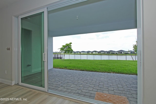 doorway featuring a residential view, baseboards, and wood finished floors