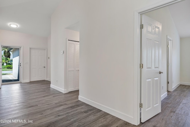 hallway with wood finished floors, baseboards, and vaulted ceiling