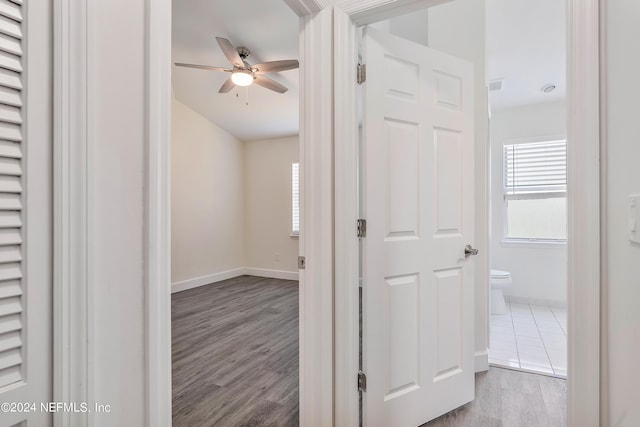 hallway with baseboards, healthy amount of natural light, and wood finished floors