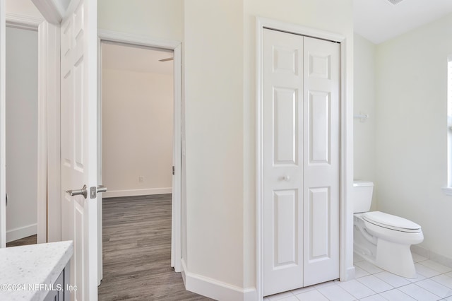 bathroom with a closet, toilet, vanity, baseboards, and tile patterned flooring