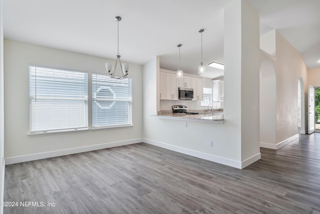 kitchen featuring appliances with stainless steel finishes, arched walkways, dark wood-style flooring, white cabinets, and a chandelier