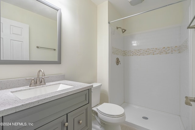bathroom featuring toilet, a tile shower, and vanity