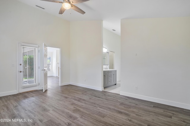 unfurnished living room featuring ceiling fan, a sink, wood finished floors, baseboards, and high vaulted ceiling