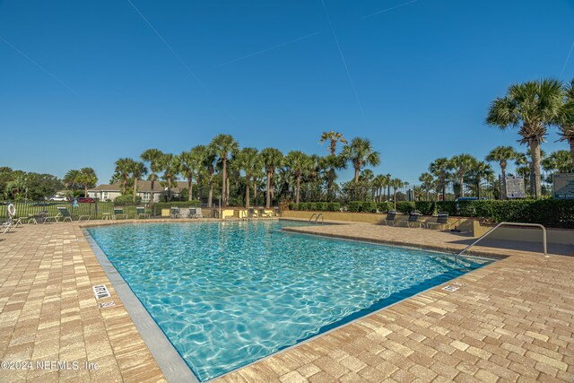 community pool with fence and a patio