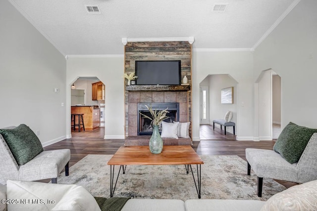 27359 Geiger Rd, Hilliard, FL 32046 - living room featuring ornamental molding, wood finished floors, arched walkways, baseboards, and a tile fireplace