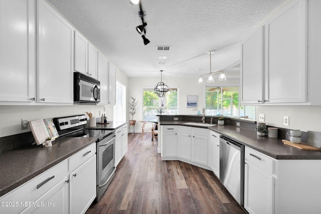 767 Mosswood Chase St, Orange Park, FL 32065 - kitchen featuring appliances with stainless steel finishes, a sink, dark countertops, dark wood-type flooring, and white cabinetry