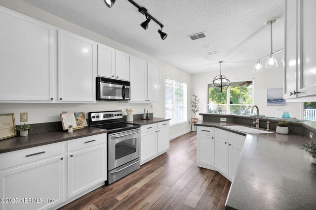 767 Mosswood Chase St, Orange Park, FL 32065 - kitchen with stainless steel appliances, a sink, dark countertops, white cabinetry, and track lighting