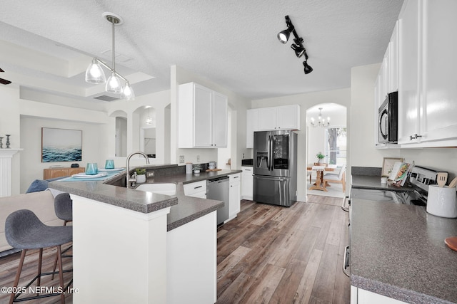 767 Mosswood Chase St, Orange Park, FL 32065 - kitchen featuring stainless steel appliances, a sink, dark countertops, arched walkways, and a chandelier