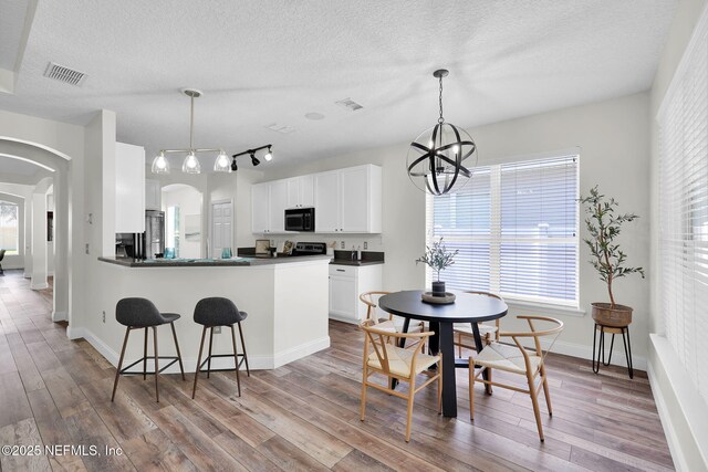 767 Mosswood Chase St, Orange Park, FL 32065 - kitchen with black microwave, arched walkways, dark countertops, a textured ceiling, and wood finished floors