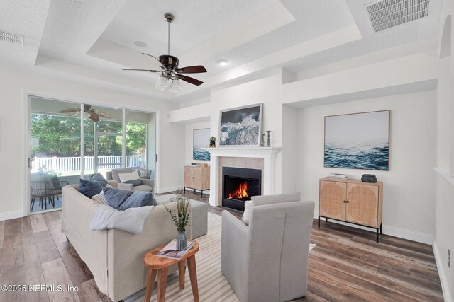767 Mosswood Chase St, Orange Park, FL 32065 - living room with a tray ceiling, a ceiling fan, wood finished floors, a fireplace, and baseboards
