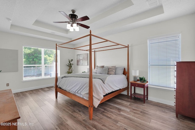 767 Mosswood Chase St, Orange Park, FL 32065 - bedroom featuring a tray ceiling, baseboards, wood finished floors, and a ceiling fan