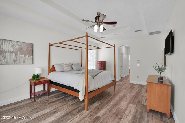 767 Mosswood Chase St, Orange Park, FL 32065 - bedroom with a raised ceiling, arched walkways, wood finished floors, baseboards, and a ceiling fan