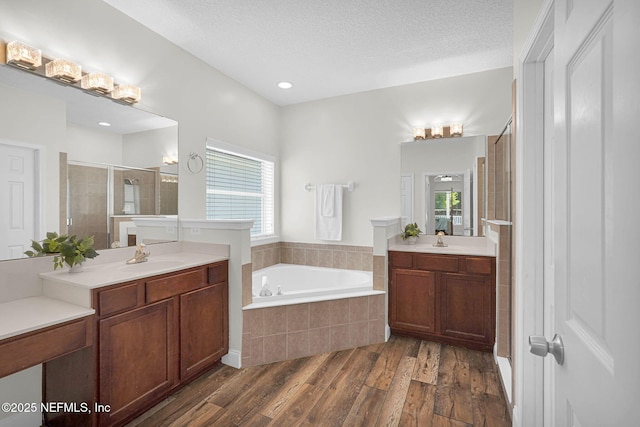 767 Mosswood Chase St, Orange Park, FL 32065 - bathroom with a stall shower, a garden tub, wood finished floors, two vanities, and a textured ceiling