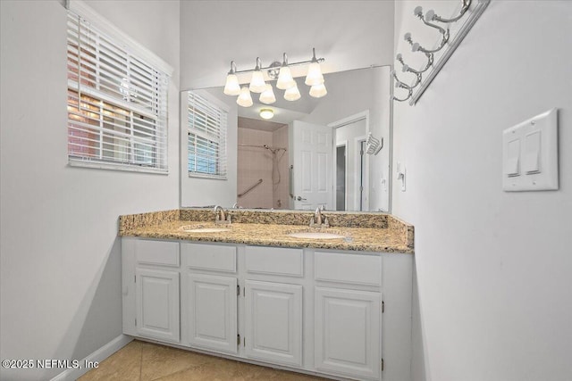 full bathroom featuring a tile shower, double vanity, tile patterned flooring, and baseboards