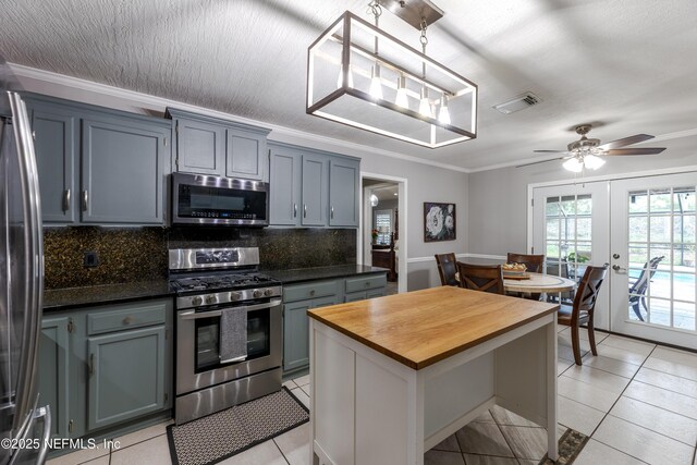 806 Falkirk Ct, Orange Park, FL 32073 - kitchen with appliances with stainless steel finishes, butcher block countertops, tasteful backsplash, light tile patterned floors, and crown molding