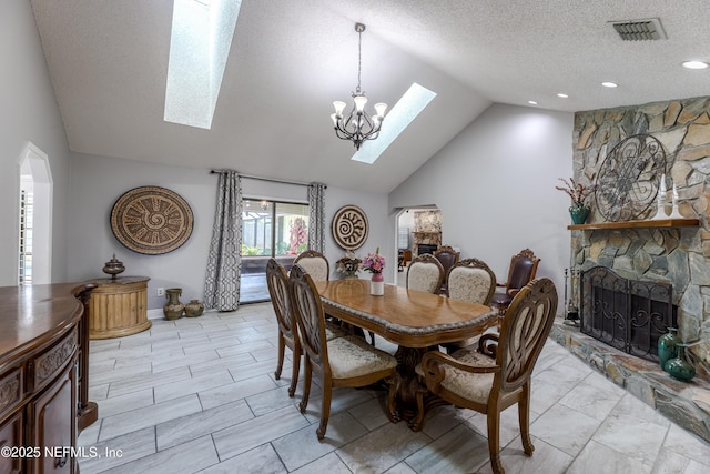 806 Falkirk Ct, Orange Park, FL 32073 - dining space featuring a skylight, vaulted ceiling, a textured ceiling, a stone fireplace, and a chandelier