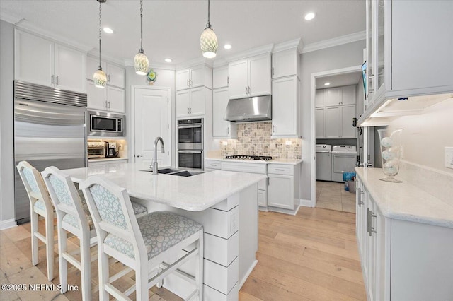 433 Marsh Cove Dr, Ponte Vedra Beach, FL 32082 - kitchen featuring built in appliances, under cabinet range hood, washing machine and dryer, crown molding, and white cabinets