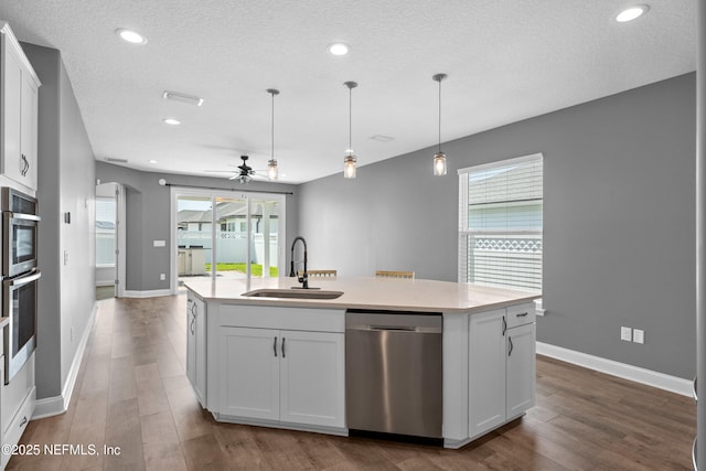 kitchen featuring dishwasher, a sink, ceiling fan, a kitchen island with sink, and wood finished floors