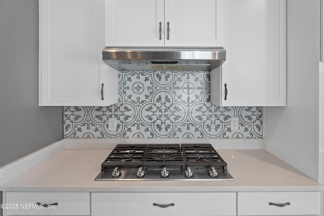 kitchen featuring stainless steel gas cooktop, under cabinet range hood, white cabinets, and backsplash