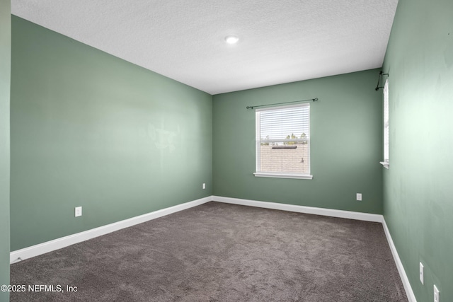 carpeted spare room featuring a textured ceiling and baseboards