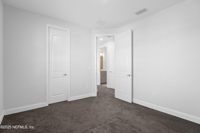 unfurnished bedroom with dark colored carpet and baseboards