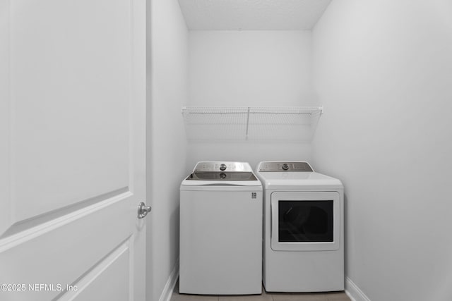 washroom featuring independent washer and dryer, baseboards, and a textured ceiling