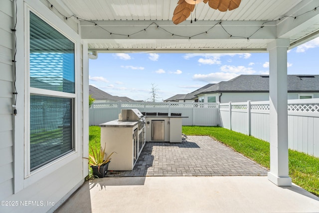 view of patio featuring exterior kitchen, a fenced backyard, area for grilling, and a ceiling fan