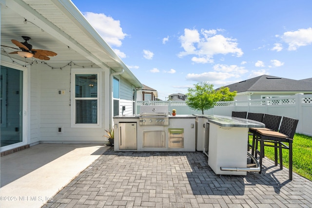 view of patio / terrace with area for grilling, exterior kitchen, a fenced backyard, and ceiling fan